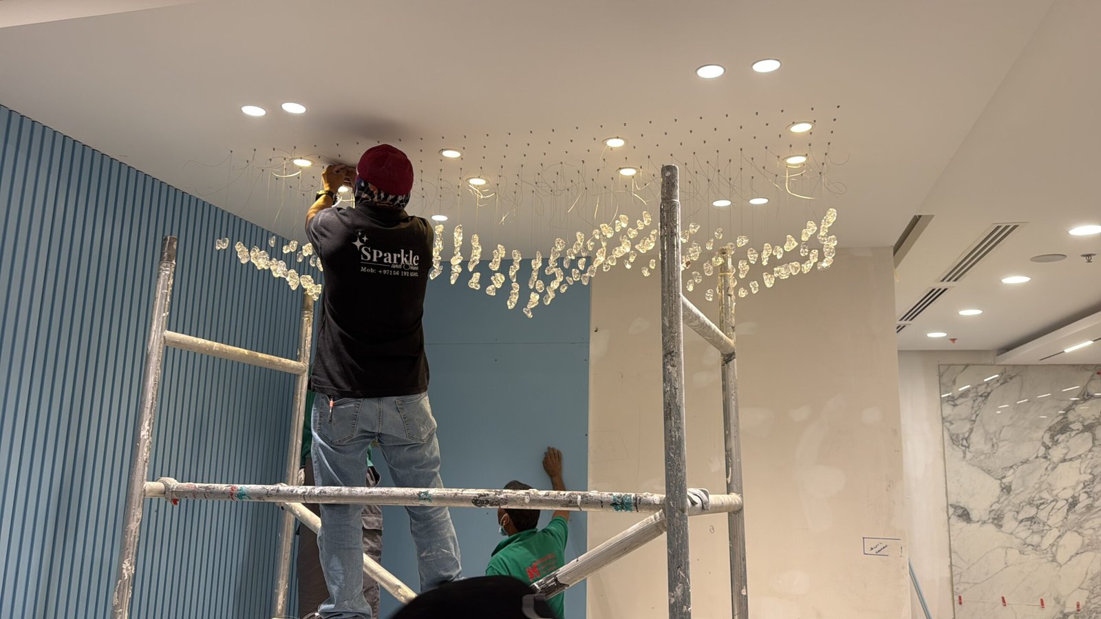 Large tiered crystal chandelier being carefully worked on by a Sparkle and Shine technician in Dubai